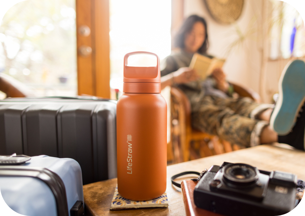 Duża litrowa butelka termiczna LifeStraw Go Steel Kyoto Orange na stoliku