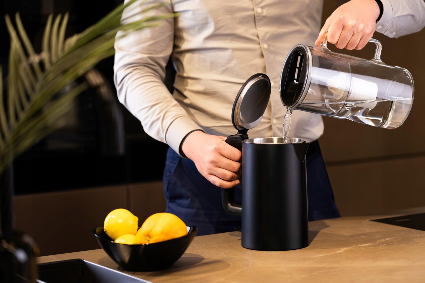 Mężczyzna napełnia czarny czajnik filtrowaną wodą z&nbsp;dzbanka Wessper WH202-BK
