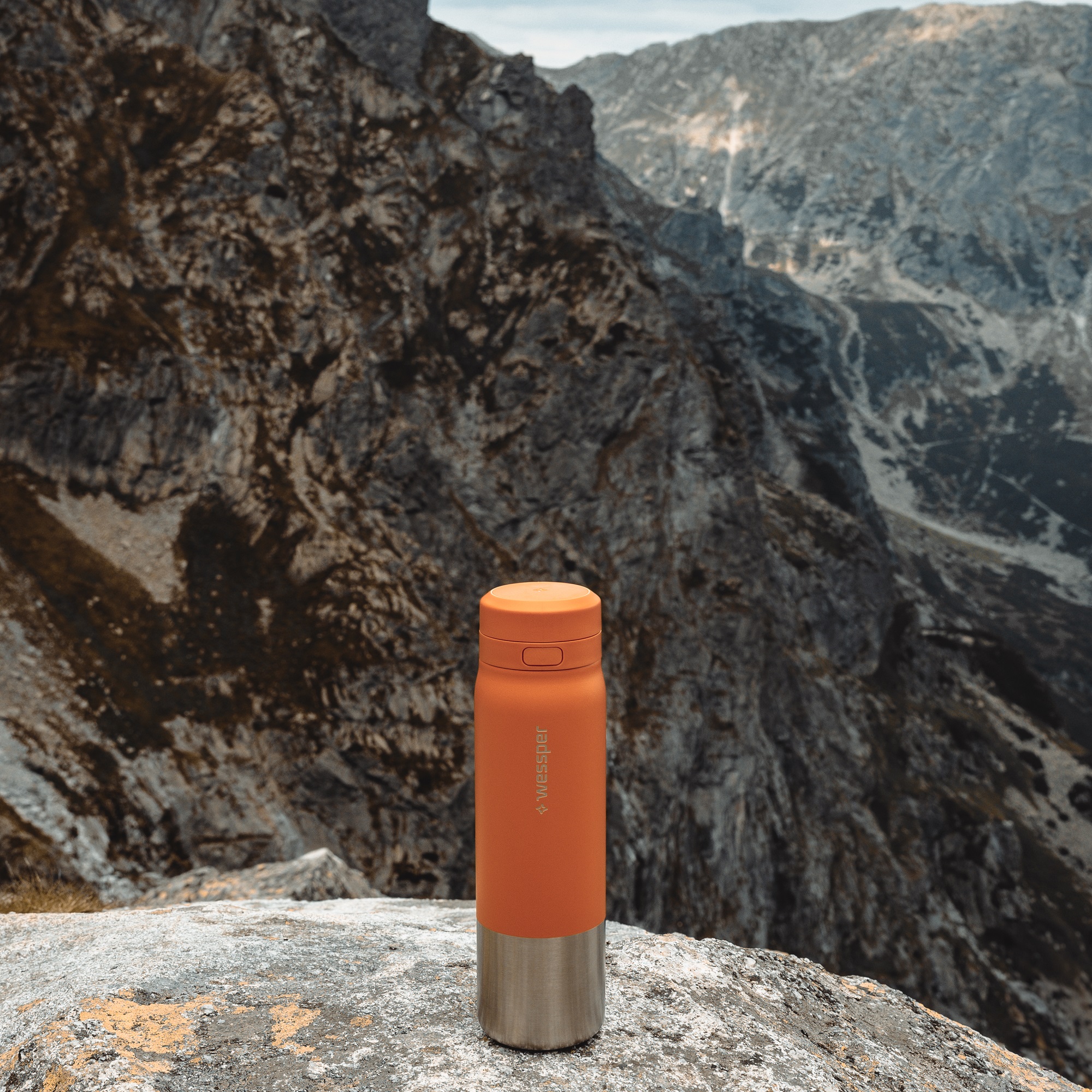 Pomarańczowa butelka ze stali nierdzewnej Wessper na tle górskiego pejzażu