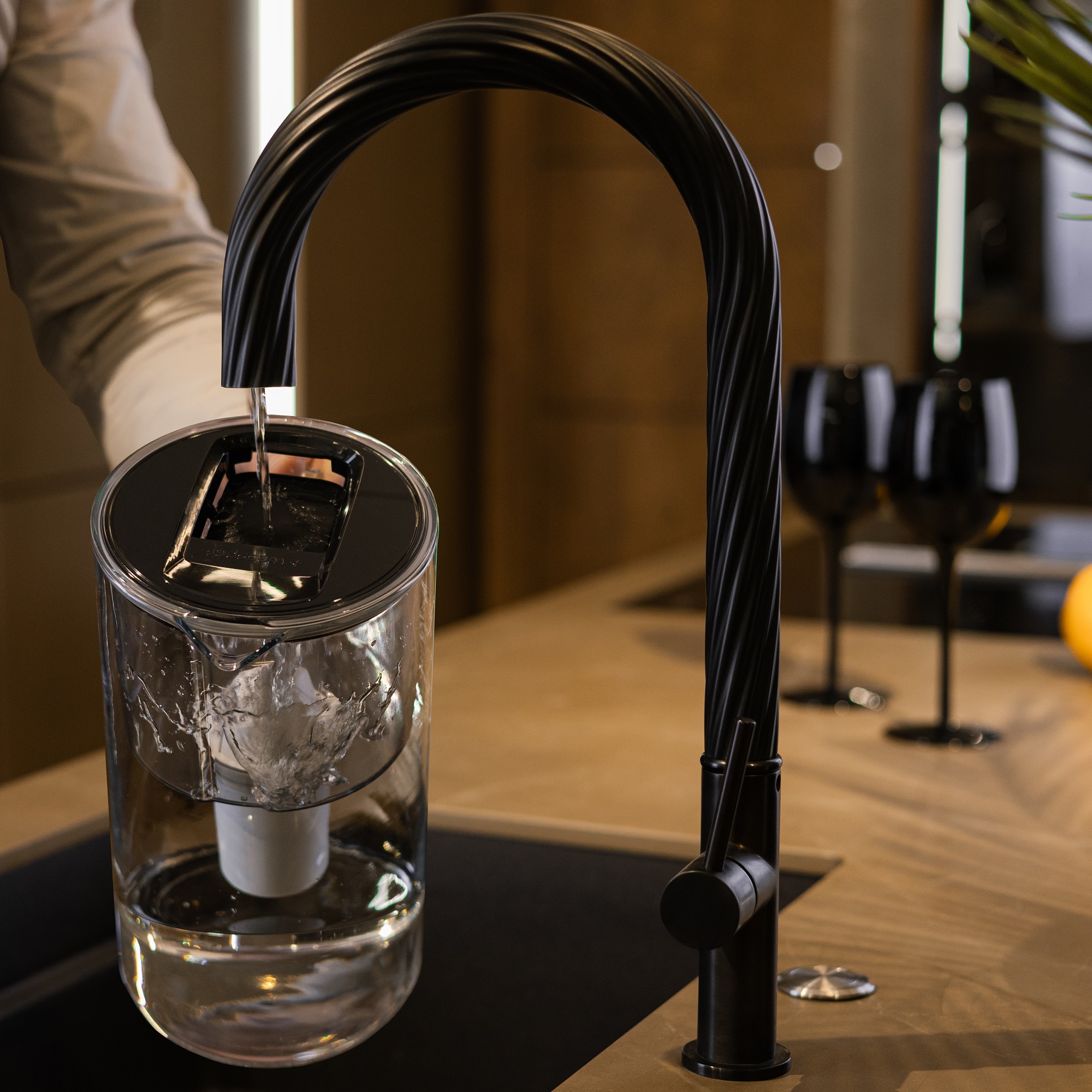 Mężczyzna napełnia dzbanek do filtrowania Wessper D2 wodą z&nbsp;eleganckiej czarnej baterii kuchenne