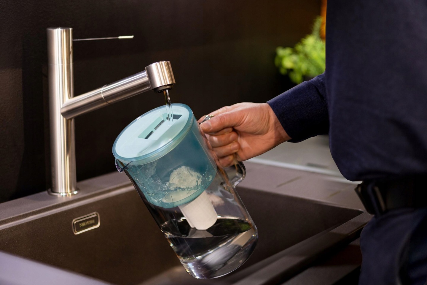 Mężczyzna napełnia dzbanek filtrujący Wessper wodą z&nbsp;baterii kuchennej