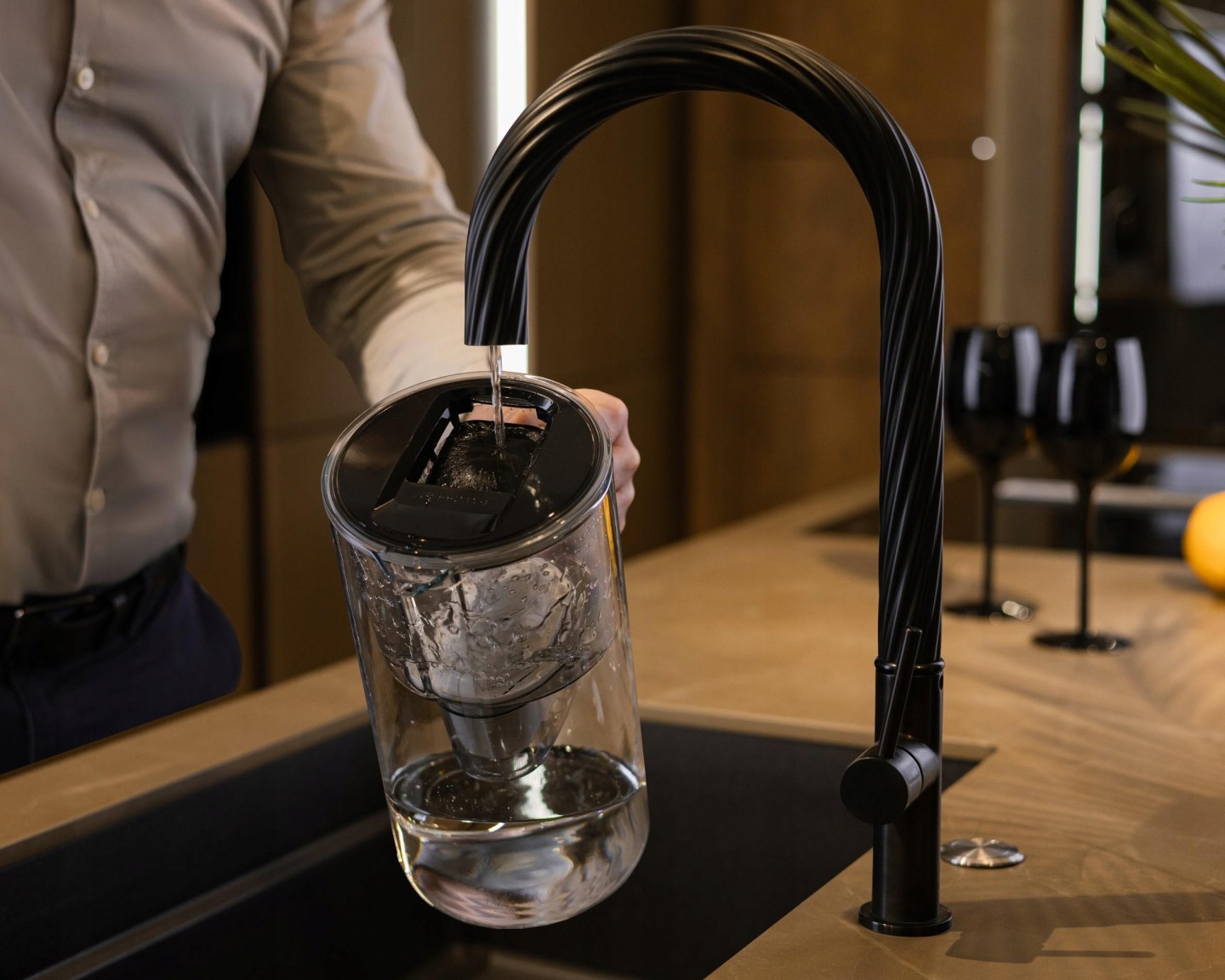 Mężczyzna napełnia dzbanek do filtrowania Wessper wodą z&nbsp;baterii kuchennej