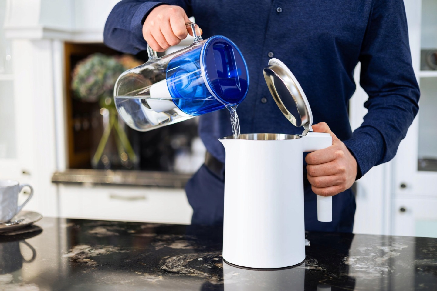 Mężczyzna napełnia przefiltrowaną wodą z&nbsp;dzbanka Wessper D2 czajnik do gotwania wody