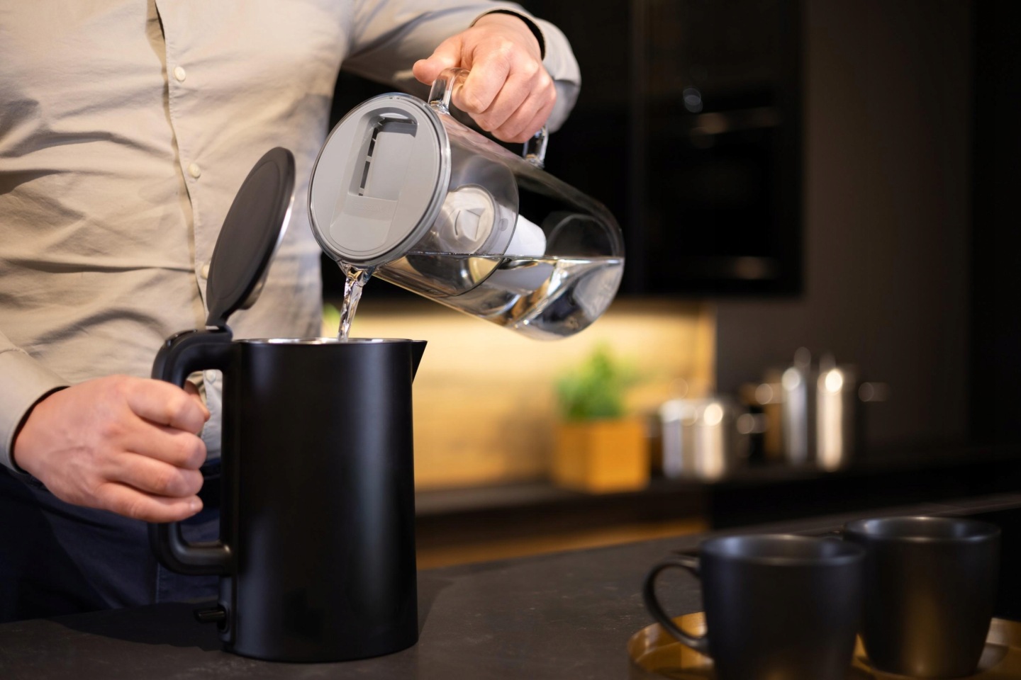 Mężczyzna nalewa wodę z&nbsp;dzbanka szklanego Wessper D2 do czajnika