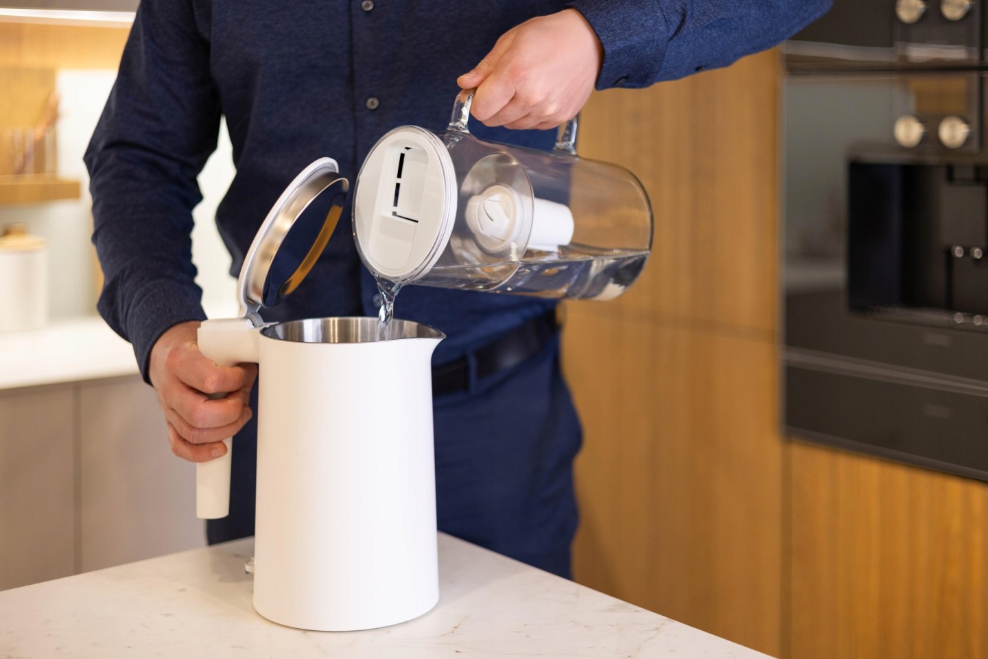 Mężczyzna nalewa wodę z&nbsp;dzbanka Wessper D2 do białego czajnika