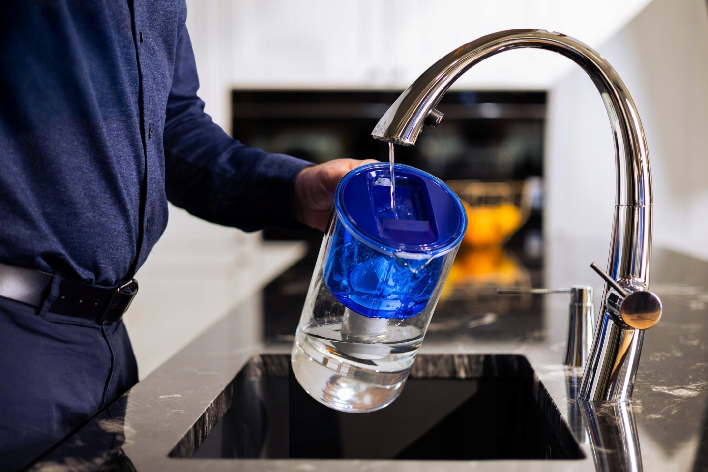 Mężczyzna napełnia dzbanek Wessper D2 Navy Blue wodą z&nbsp;kuchennej baterii